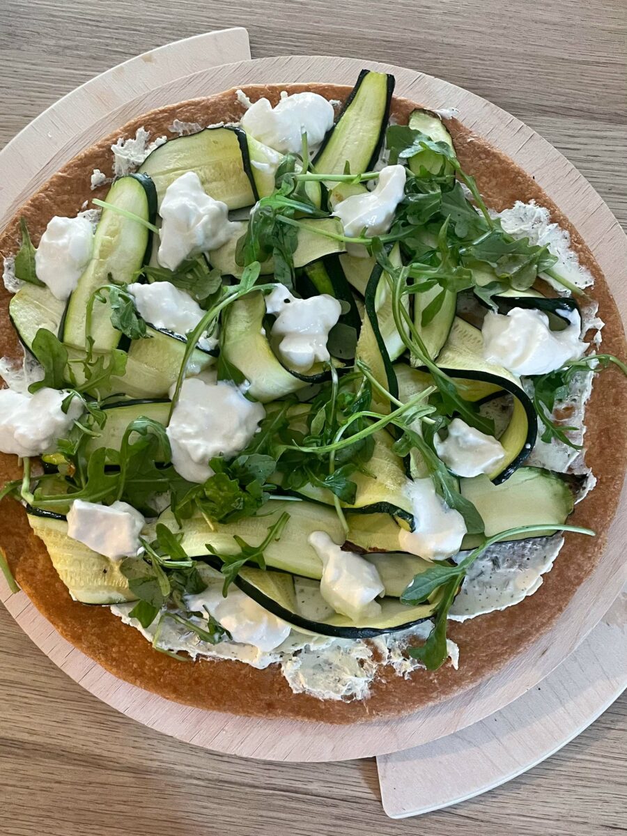 Puis ajoutez la roquette, la burrata et les olives sur le dessus.
